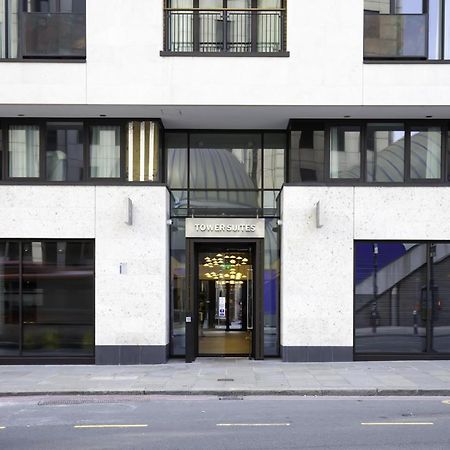 Tower Suites By Blue Orchid London Exteriör bild The image shows the entrance of a modern building, characterized by its minimalist architectural design. The facade features a combination of large glass windows and smooth stone surfaces. The entrance is framed by glass doors, flanked by stylish lig