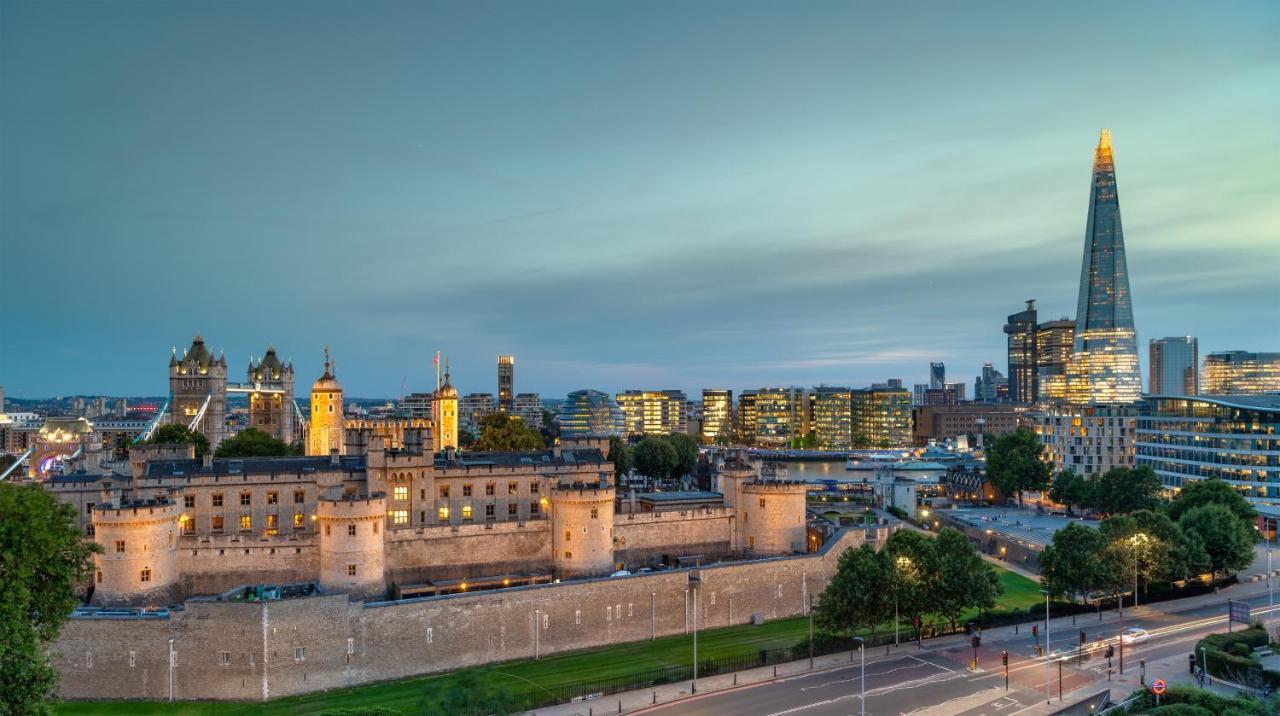 Tower Suites By Blue Orchid London Exteriör bild The photo shows a view of a historical site and modern skyline. In the foreground, there is a prominent historical building, likely a castle or fortress, featuring tall towers and a stone wall. This structure is set against a backdrop of contemporary