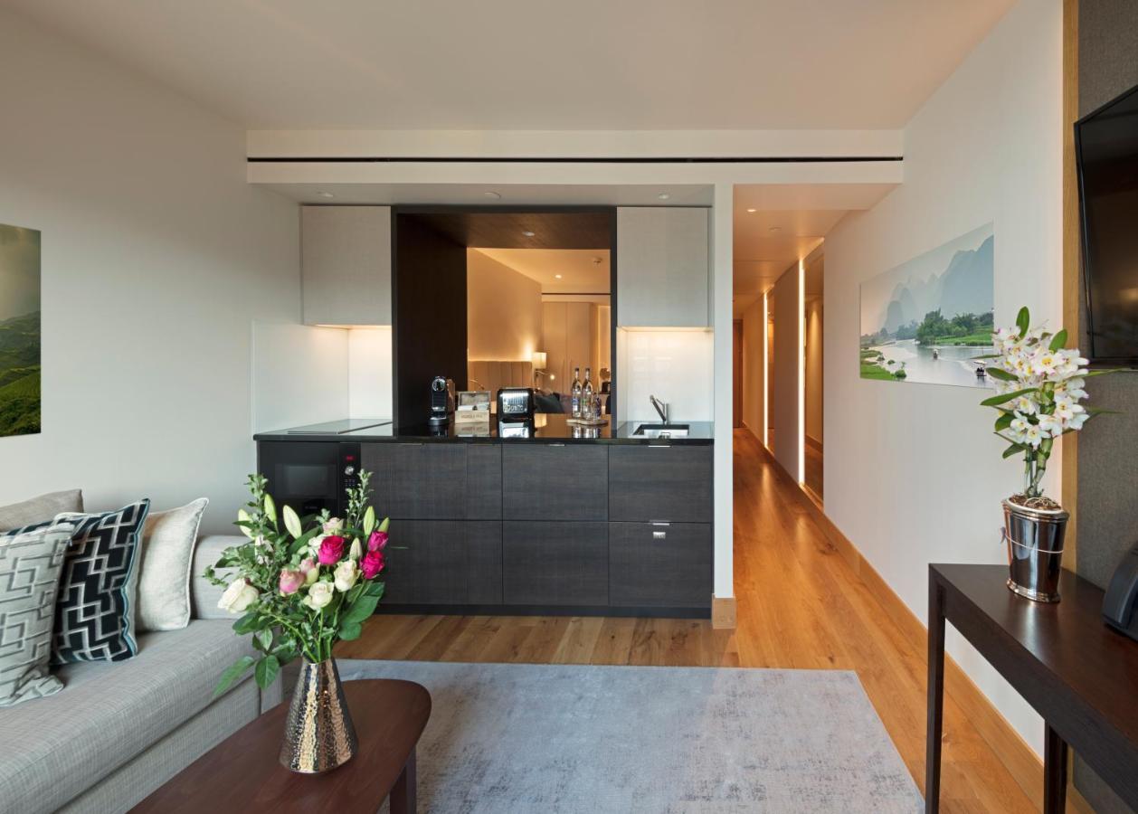 Tower Suites By Blue Orchid London Exteriör bild The photo showcases a modern and stylish interior space, likely a living area of a luxurious apartment or hotel suite. 

- **Bar Area**: There is a sleek bar counter that features a variety of bottles and glassware, suggesting a well-equipped space f