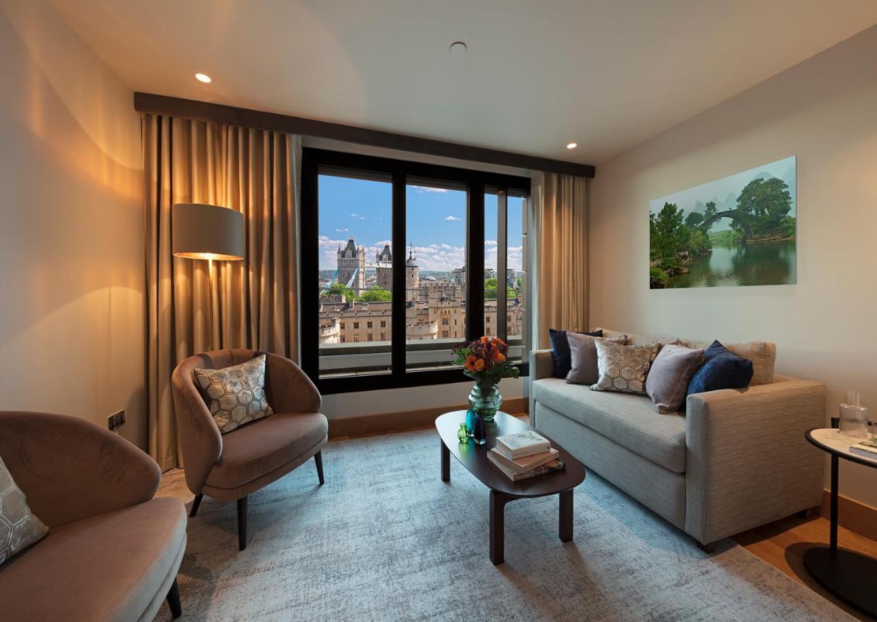 Tower Suites By Blue Orchid London Exteriör bild The photo depicts a modern living room with a contemporary design. It features two stylish, circular chairs and a comfortable sofa adorned with various decorative pillows. A small coffee table is positioned in front of the sofa, topped with books and