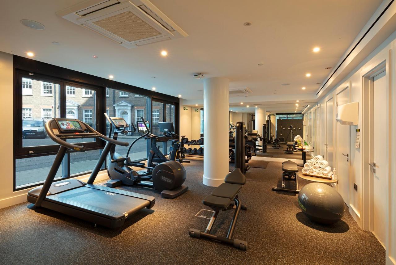 Tower Suites By Blue Orchid London Exteriör bild The photo shows a modern gym interior featuring various exercise equipment. On one side, there are several cardio machines, including treadmills and an elliptical. The gym has a spacious, bright feel with large windows allowing natural light to enter