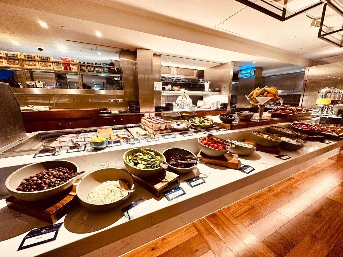 Tower Suites By Blue Orchid London Exteriör bild The photo shows a well-organized buffet spread. There are several bowls filled with various ingredients, likely for a meal or a salad bar. The ingredients include different types of vegetables, fruits, and possibly some grains or legumes. In the back