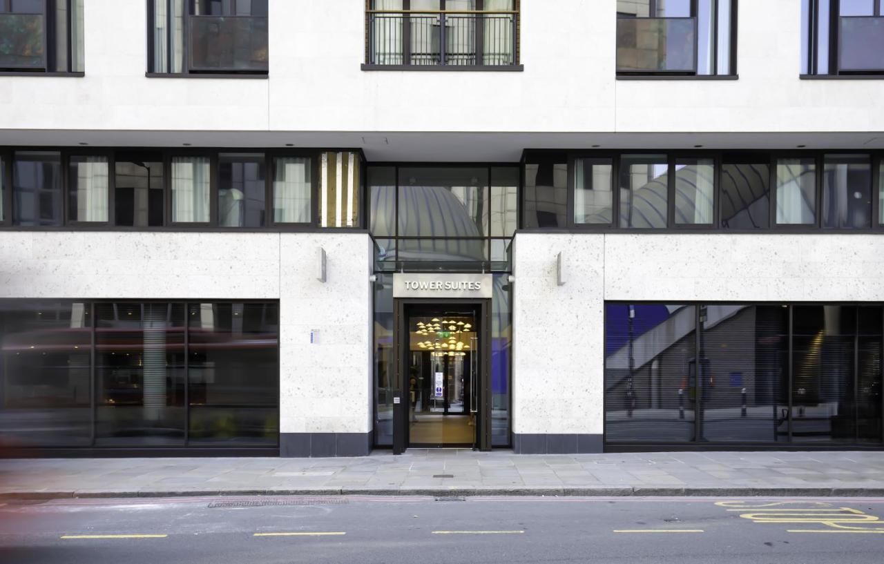 Tower Suites By Blue Orchid London Exteriör bild The image shows the entrance of a modern building, characterized by its minimalist architectural design. The facade features a combination of large glass windows and smooth stone surfaces. The entrance is framed by glass doors, flanked by stylish lig
